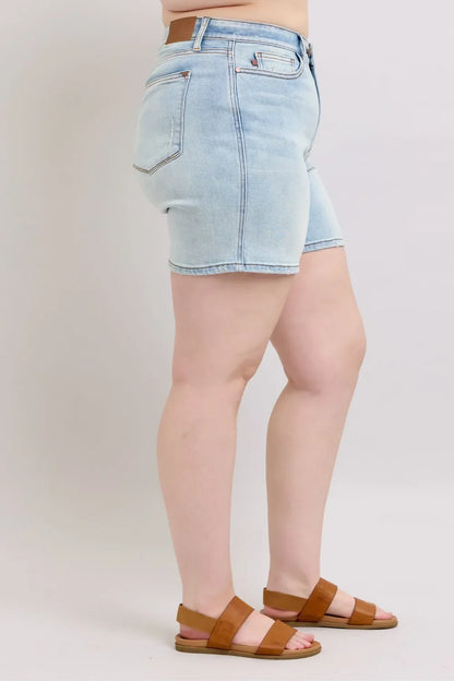 Woman wearing light wash denim shorts and brown sandals, side view