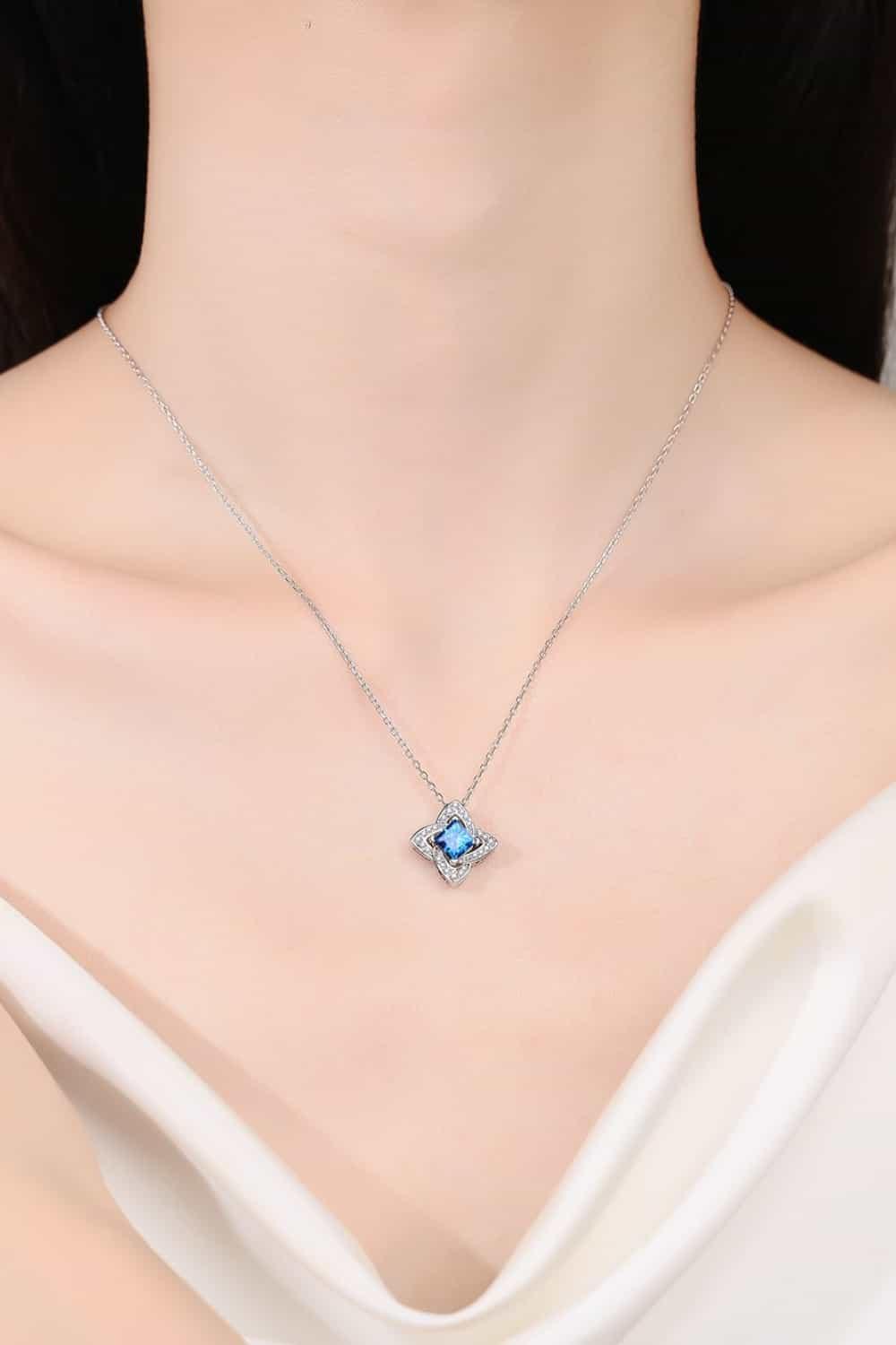 Elegant woman wearing silver chain necklace with blue gemstone pendant