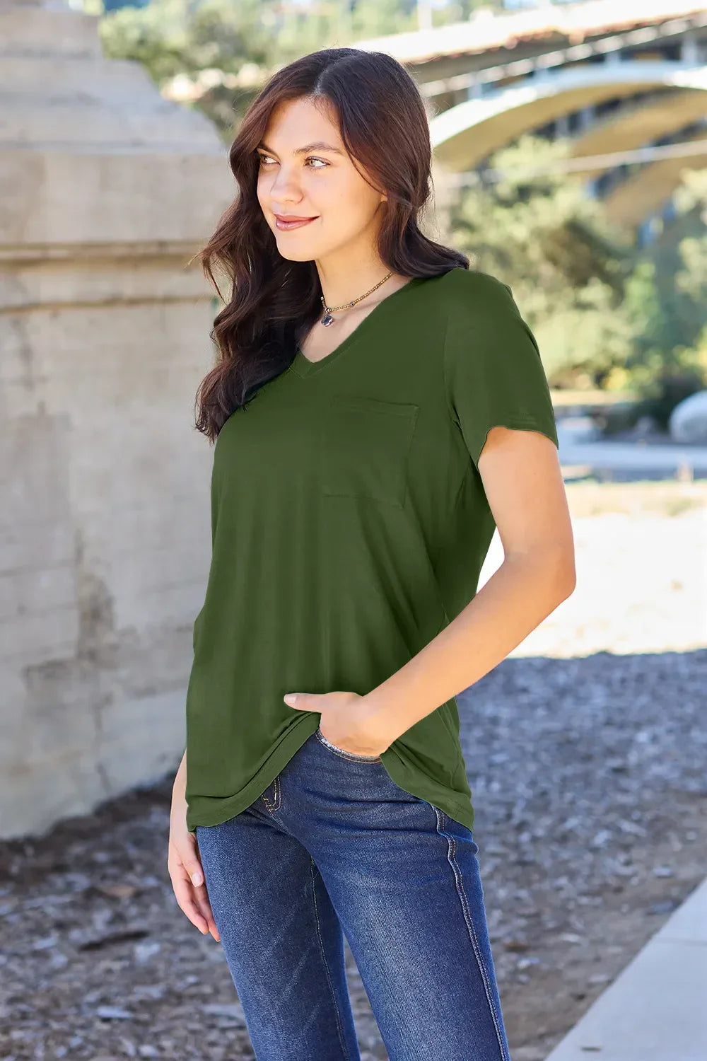 Woman outdoors wearing olive green short sleeve pocket tee and blue jeans