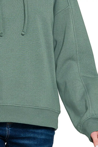 Sage green oversized sweatshirt with dropped shoulders and blue denim jeans