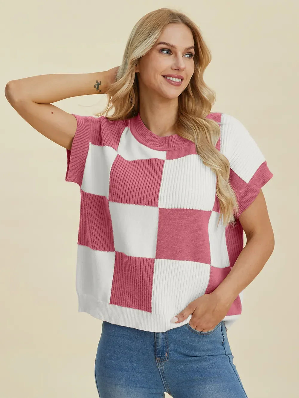 Woman wearing a pink and white checkered knit short-sleeve top with blue jeans