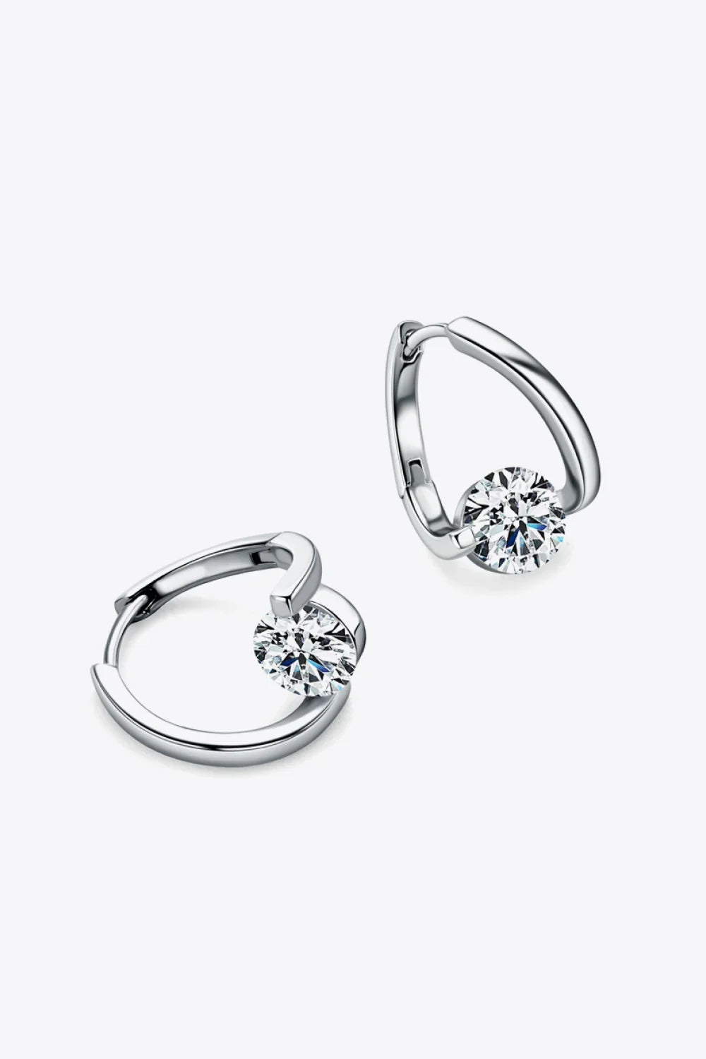 Pair of silver hoop earrings with round clear gemstone accent on light background