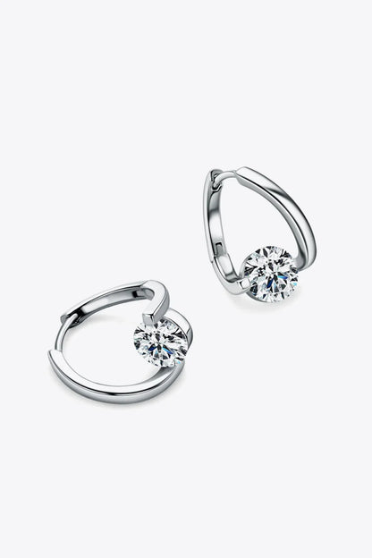 Pair of silver hoop earrings with round clear gemstone accent on light background