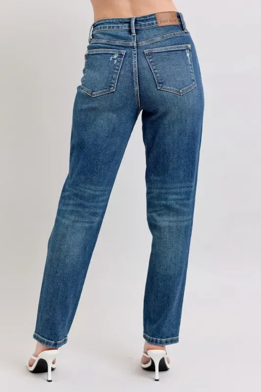 Back view of woman wearing high-waisted straight leg blue jeans and white heeled sandals