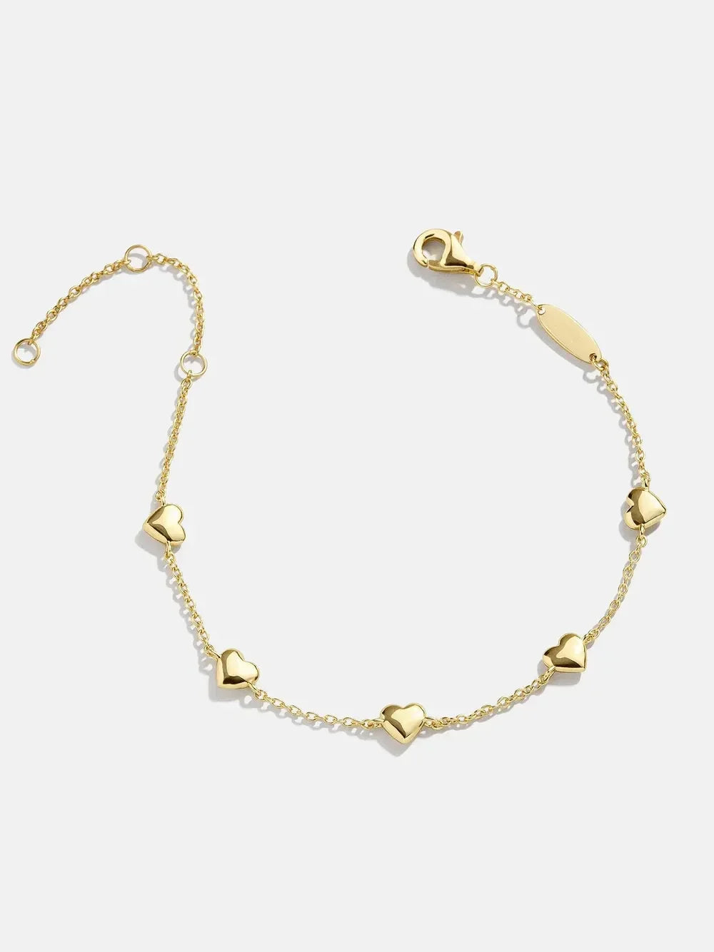 Delicate gold bracelet with heart charms on a white background