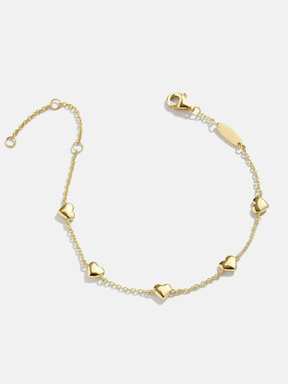 Delicate gold bracelet with heart charms on a white background
