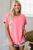 Woman wearing a bright pink ruffle hem blouse with light denim shorts indoors