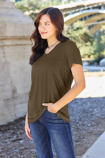 Woman wearing an olive green short sleeve pocket tee and blue jeans outdoors