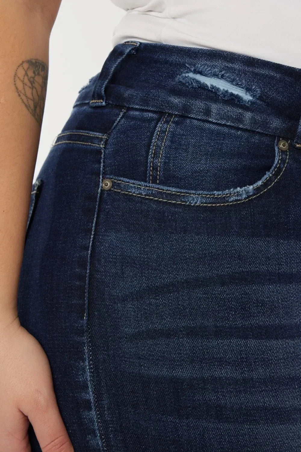 Closeup of dark wash distressed denim jeans with front pocket and belt loop detailing