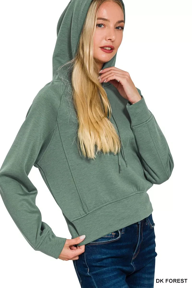 Woman wearing dark green hooded sweatshirt with relaxed fit and blue jeans