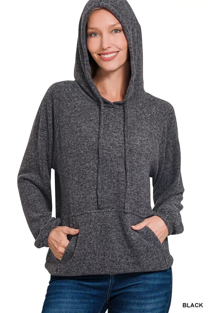 Woman wearing a charcoal gray hooded sweater with front pocket and relaxed fit