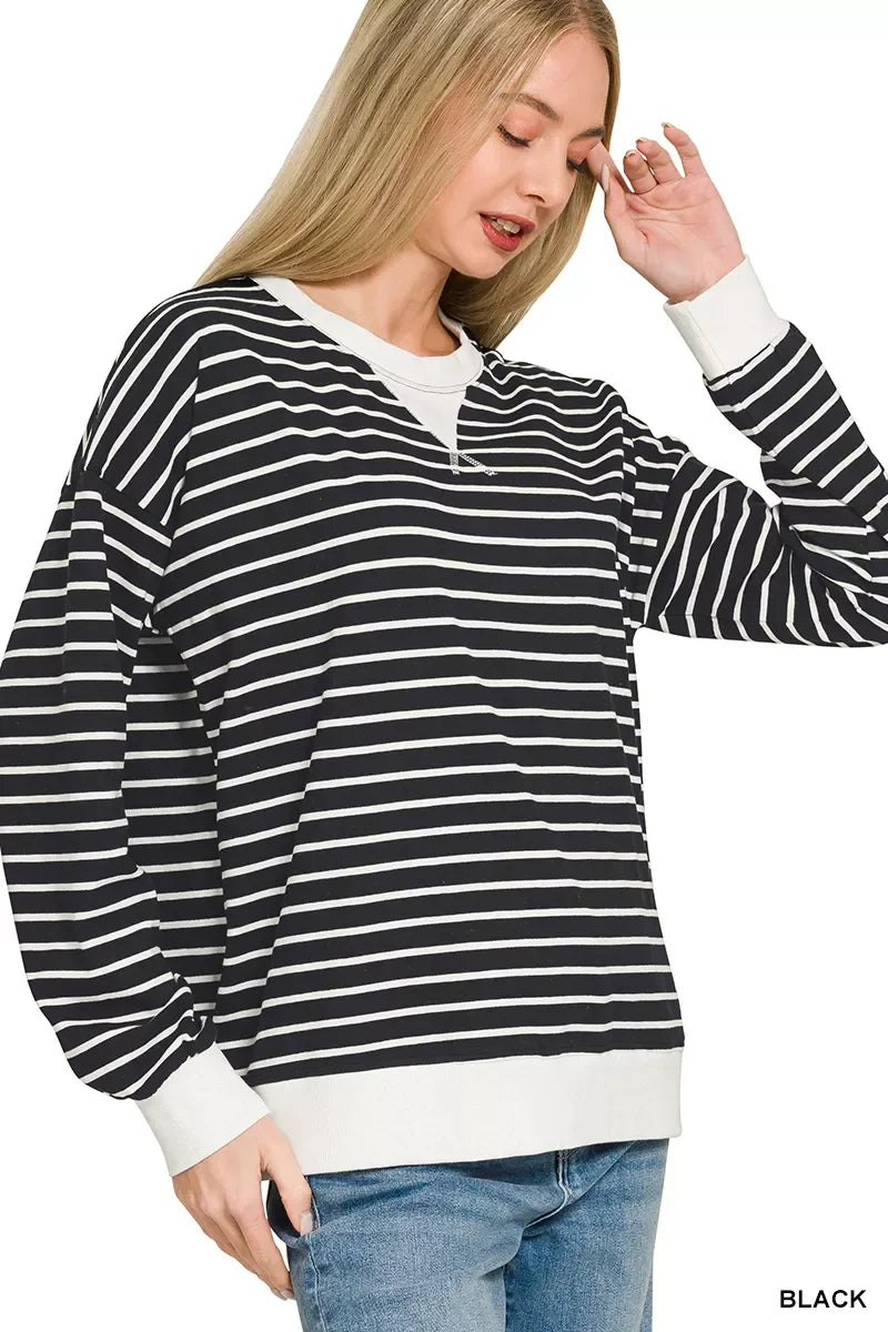 Woman wearing black and white striped long sleeve pullover with white cuffs and blue jeans