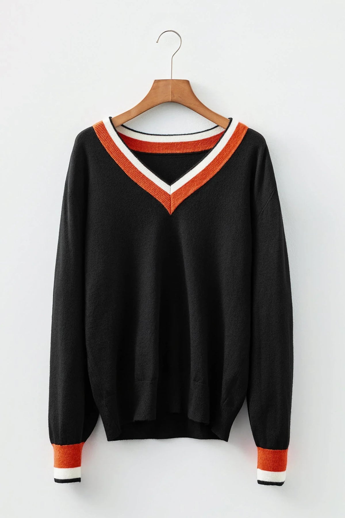 Black V-neck sweater with orange and white trim on collar and cuffs, hanging on wooden hanger