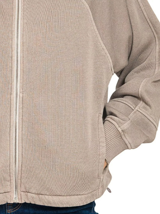Beige zip-up jacket with relaxed fit and ribbed cuffs, styled with blue jeans