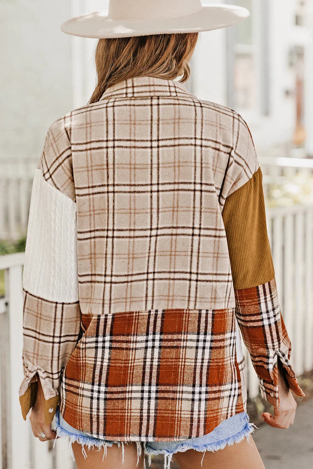 Woman wearing a beige plaid patchwork shirt with mixed fabric sleeves and denim shorts