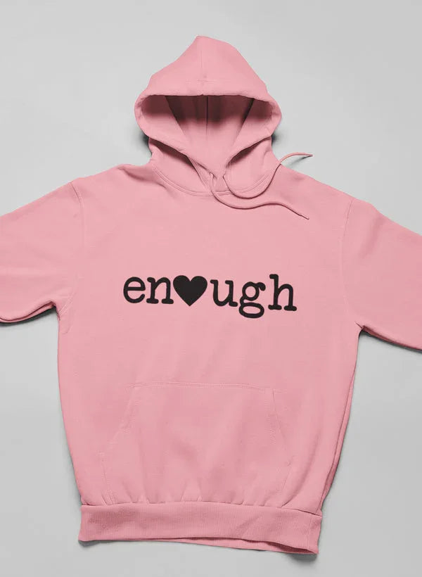Pink hoodie with 'enough' text and heart graphic on front, laid flat on gray background.