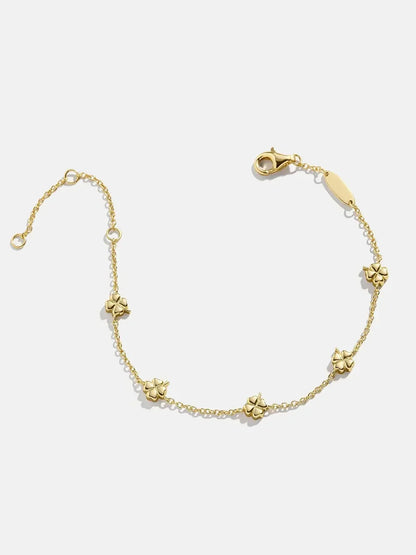 Delicate gold chain bracelet with small flower charms on a white background