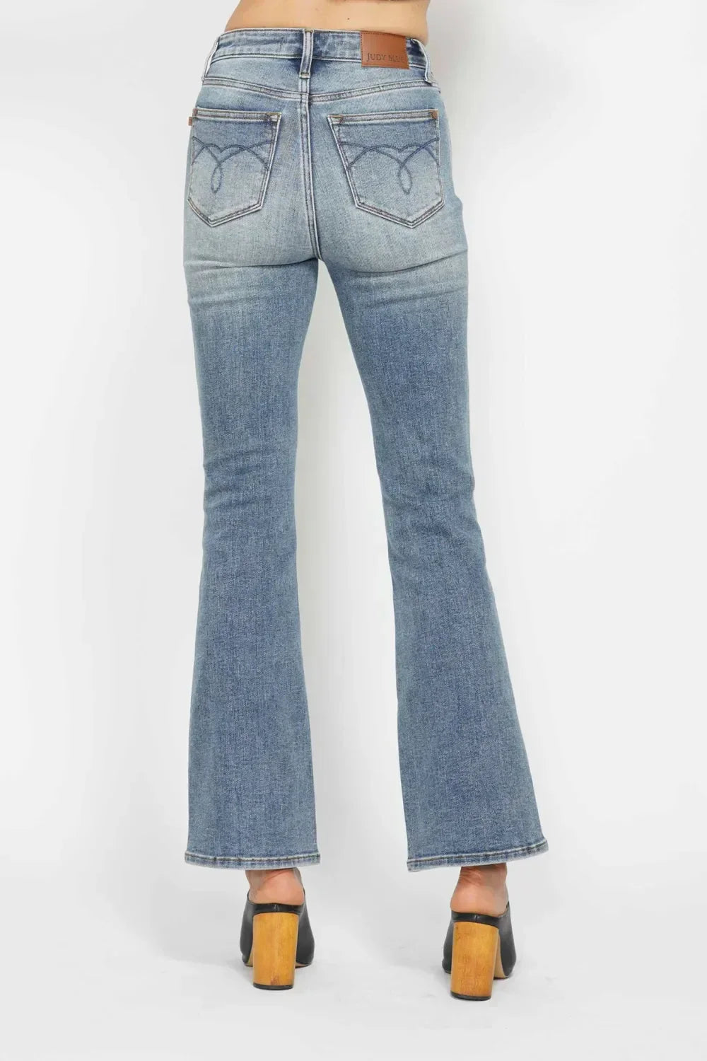 Back view of woman wearing high-waisted flare jeans and black platform heels