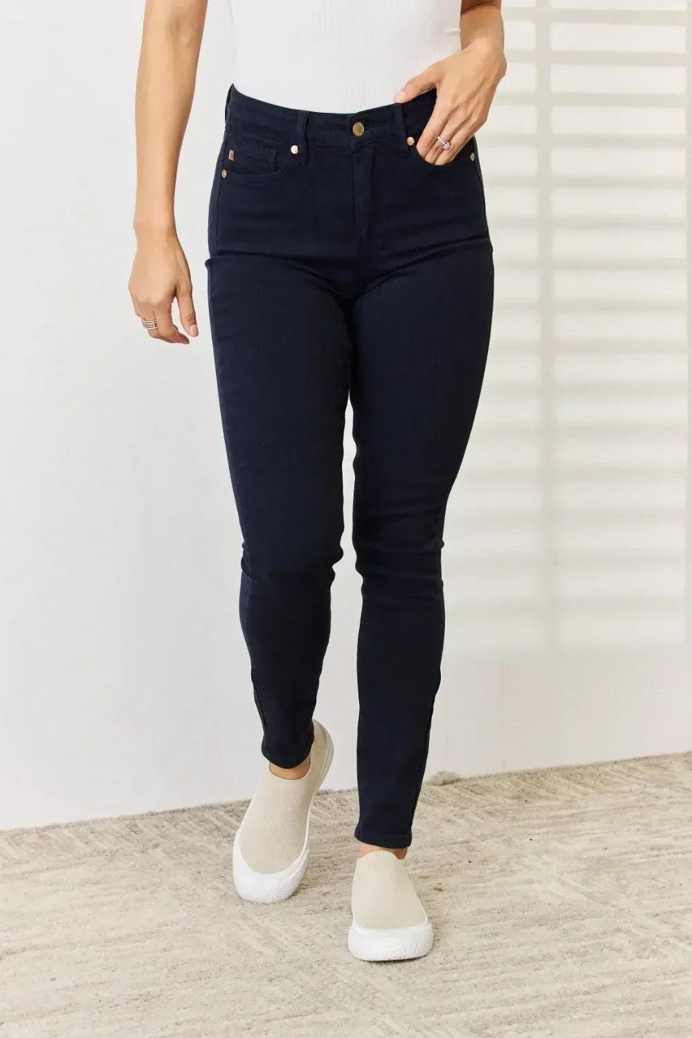 Woman wearing high-waisted dark skinny jeans and beige slip-on shoes indoors