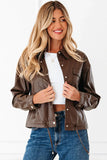 Woman wearing a brown faux leather jacket, white crop top, and blue jeans against a white background.