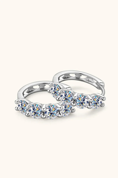 Pair of silver hoop earrings with five round clear gemstones on each, minimalist background