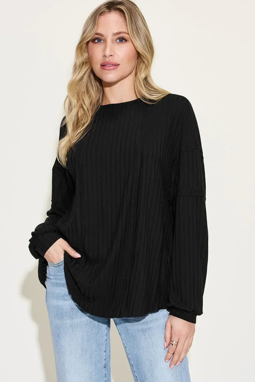 Woman wearing a relaxed fit black ribbed long sleeve top with light blue jeans