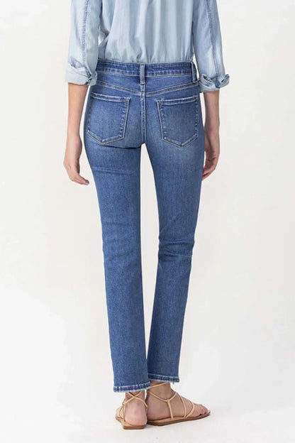Back view of woman in straight leg blue jeans, chambray shirt, and flat sandals