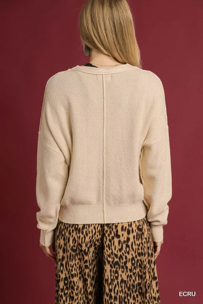 Back view of woman in textured ecru sweater and leopard print skirt against maroon background