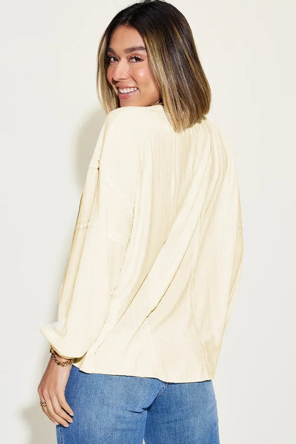 Woman wearing a cream long-sleeve blouse with relaxed fit and blue jeans, smiling