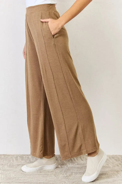 Woman wearing relaxed-fit brown wide leg pants with pockets and white slip-on shoes