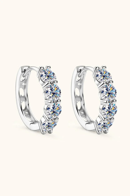 Pair of silver hoop earrings with five round clear gemstones on each, displayed on light background.