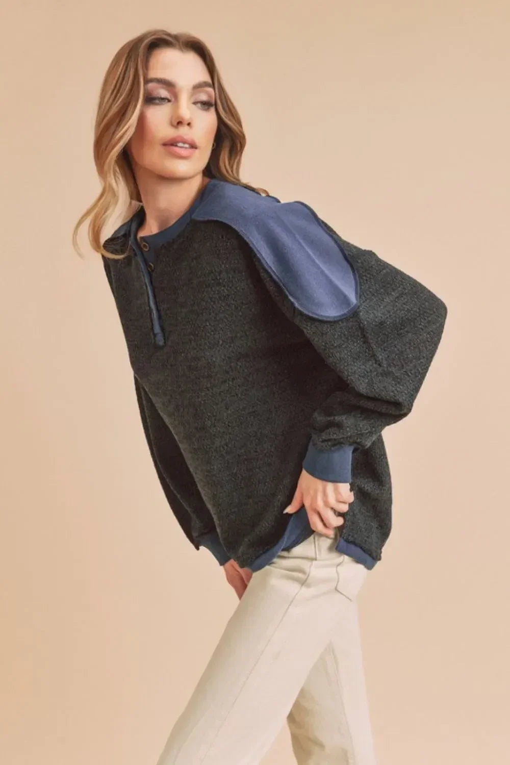 Woman wearing a modern color block pullover sweater with relaxed fit and cream pants