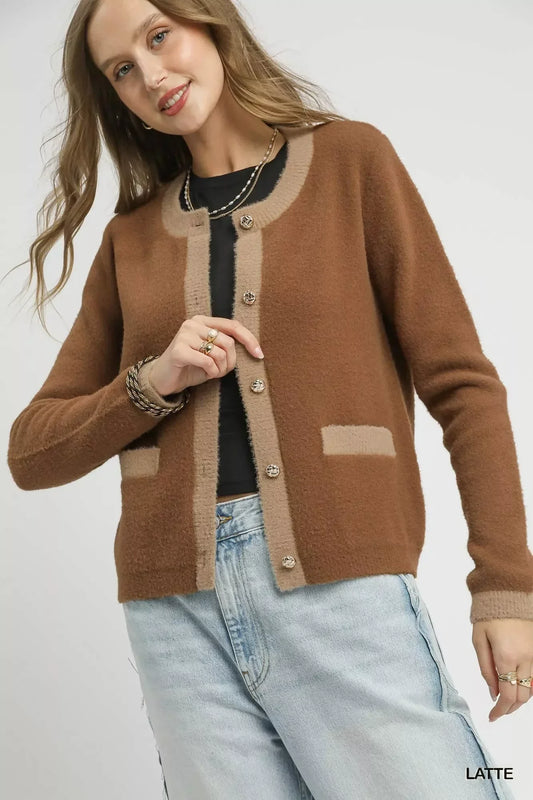 Woman wearing a brown knit cardigan with beige trim and gold buttons, styled with jeans