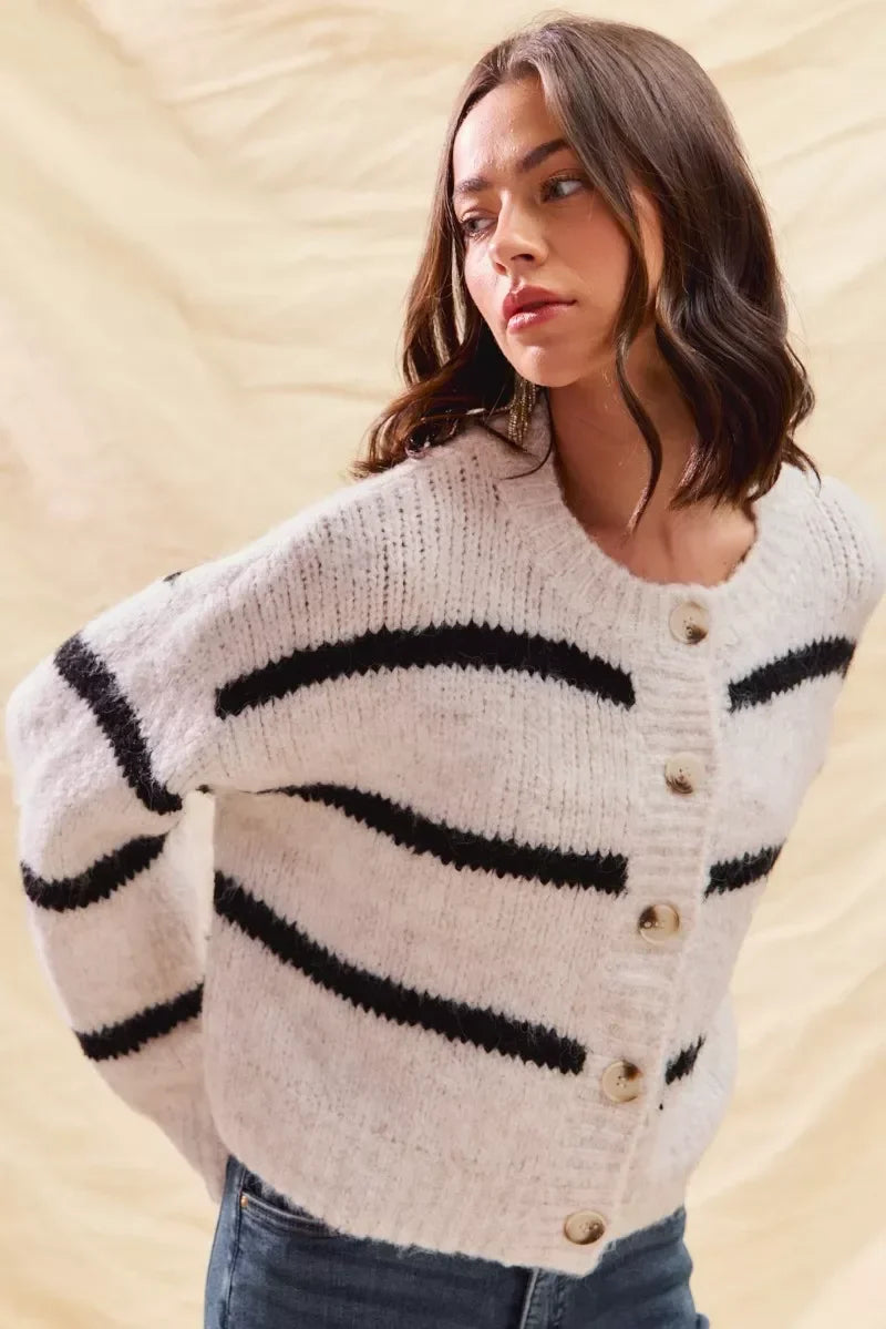 Woman wearing a cozy white button-up sweater with black horizontal stripes and casual jeans