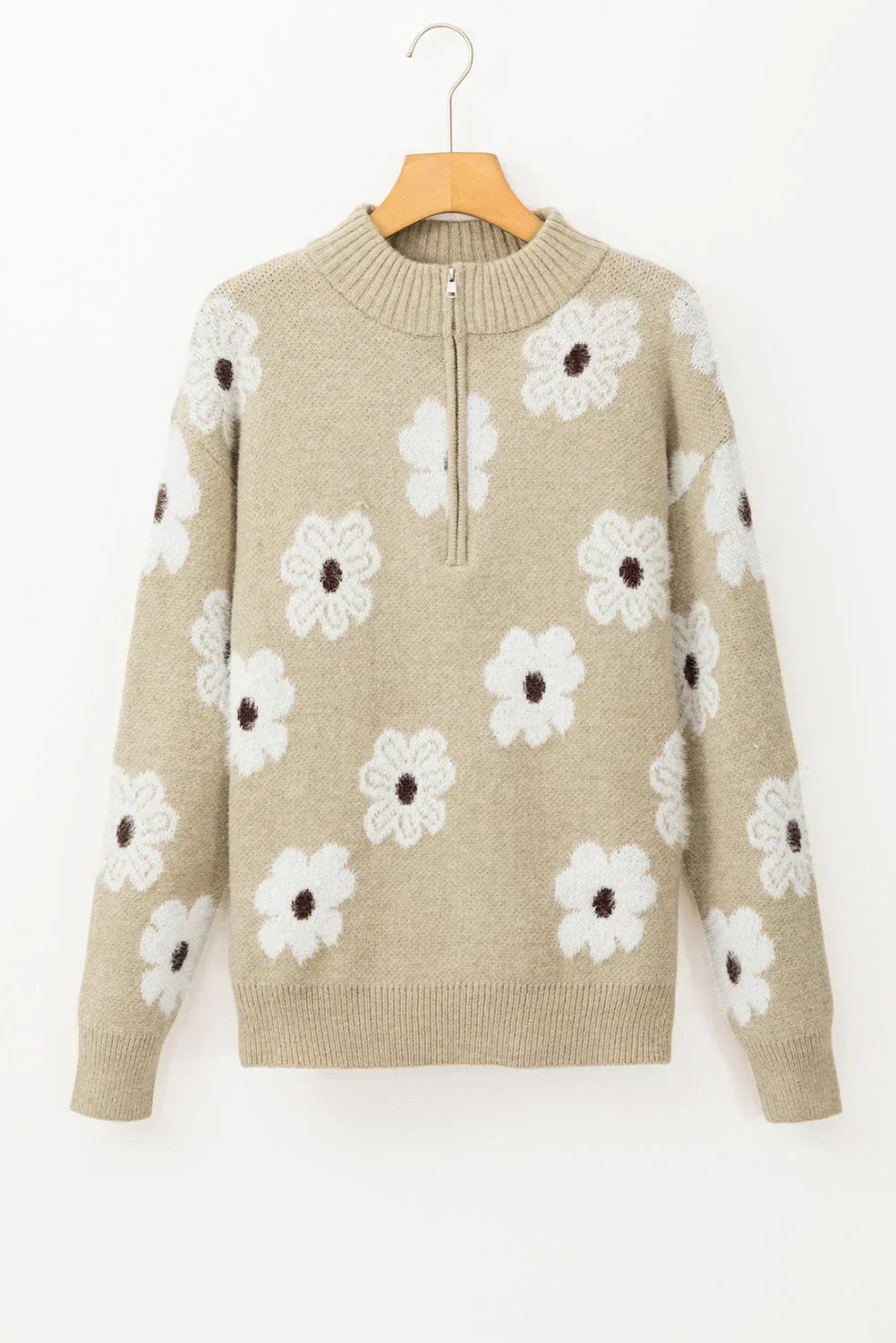 Beige knit pullover sweater with white daisy floral pattern and half-zip collar, hanging on hanger.