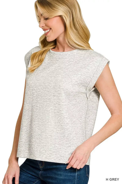 Woman wearing a light heather grey sleeveless top with rolled cuffs and blue jeans
