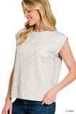 Woman wearing a light heather grey sleeveless top with rolled cuffs and blue jeans