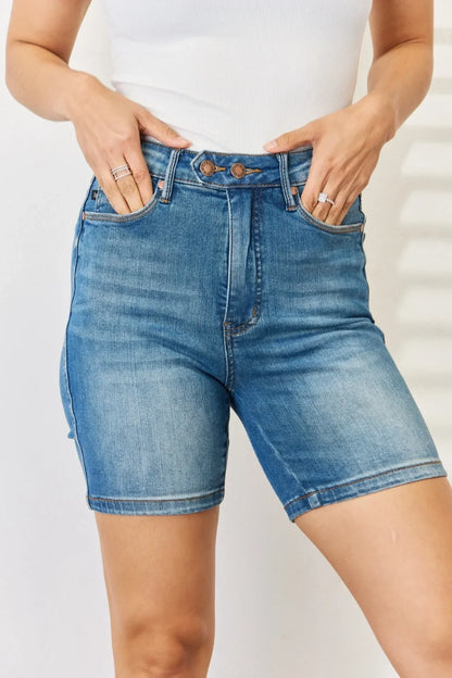 High-waisted denim bermuda shorts with double button closure, modeled with white top.
