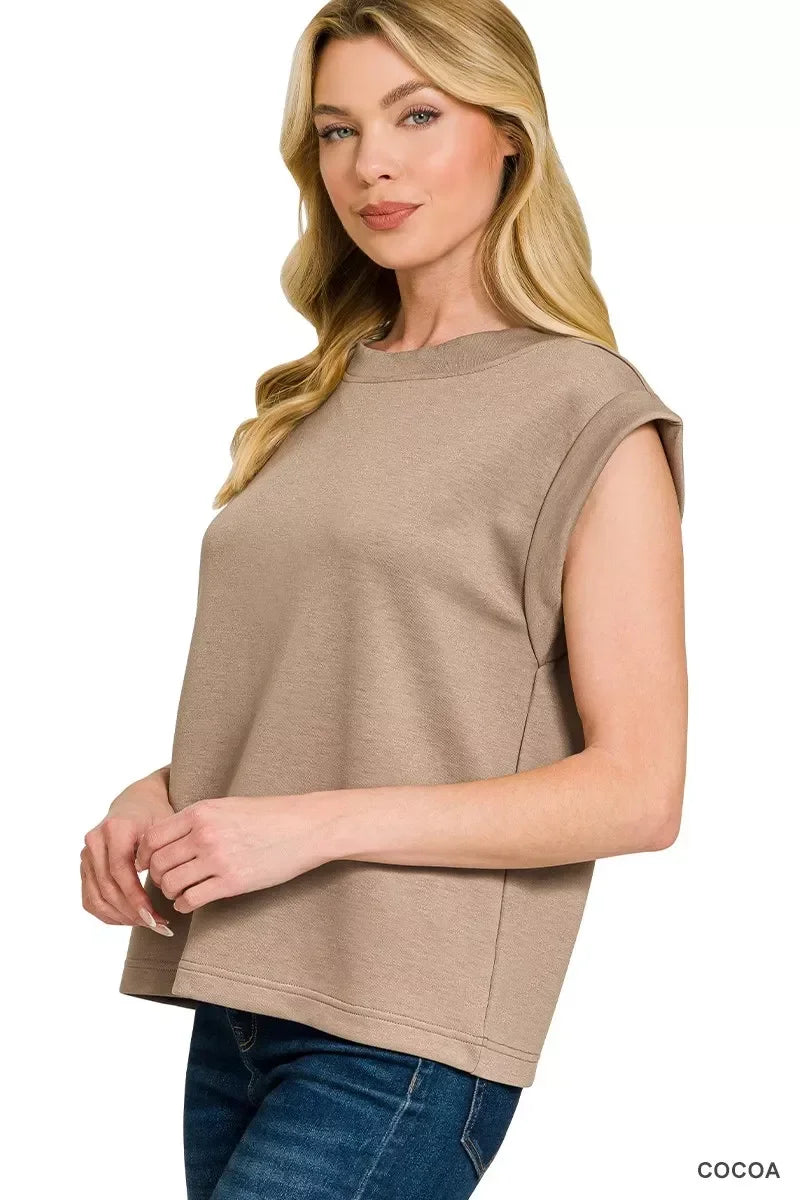 Woman wearing a sleeveless cocoa-colored top with relaxed fit and blue jeans.