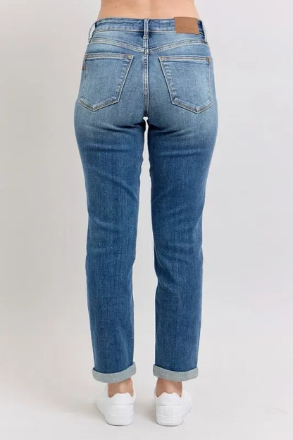Back view of woman wearing relaxed fit blue jeans with cuffed hems and white sneakers