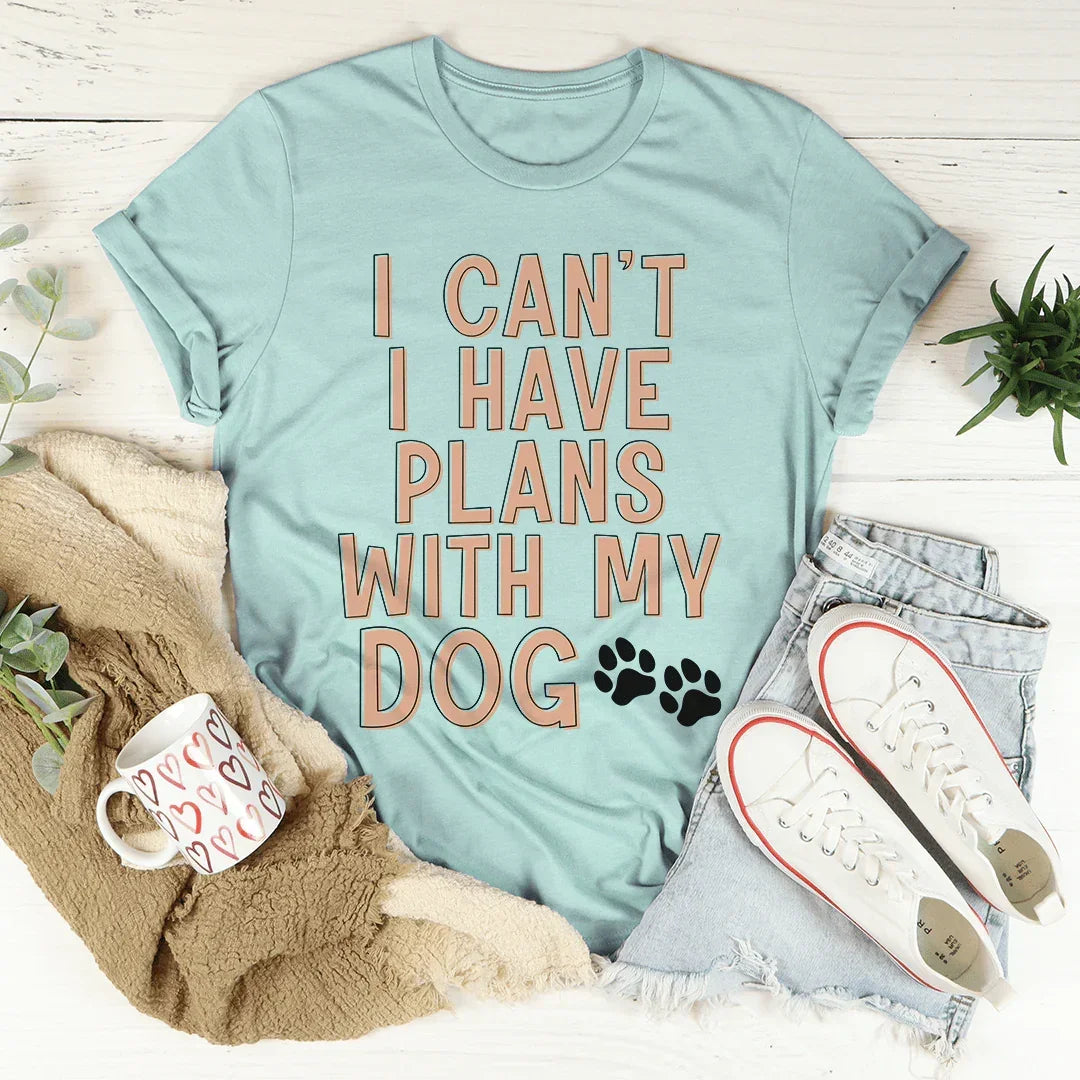 Heather blue graphic tee with 'I Can't I Have Plans With My Dog' text, styled with denim shorts and sneakers.