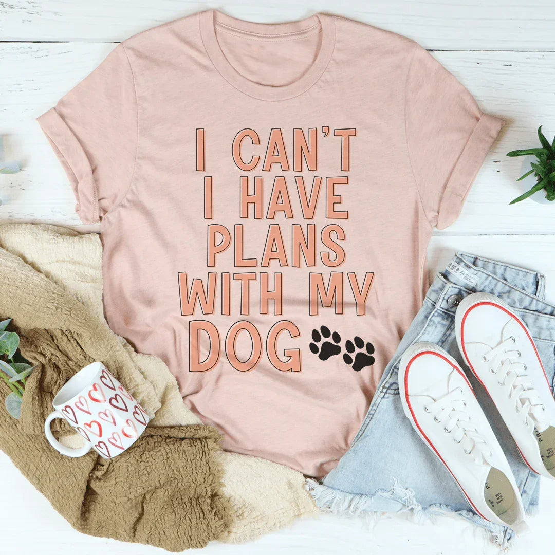 Peach graphic tee with 'I can't I have plans with my dog' text, styled with denim shorts and sneakers.