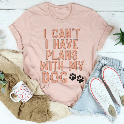 Peach graphic tee with 'I can't I have plans with my dog' text, styled with denim shorts and sneakers.