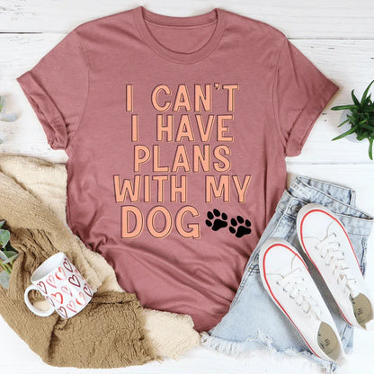 Mauve graphic tee with 'I can't I have plans with my dog' text and paw prints, styled with denim shorts and white sneakers.