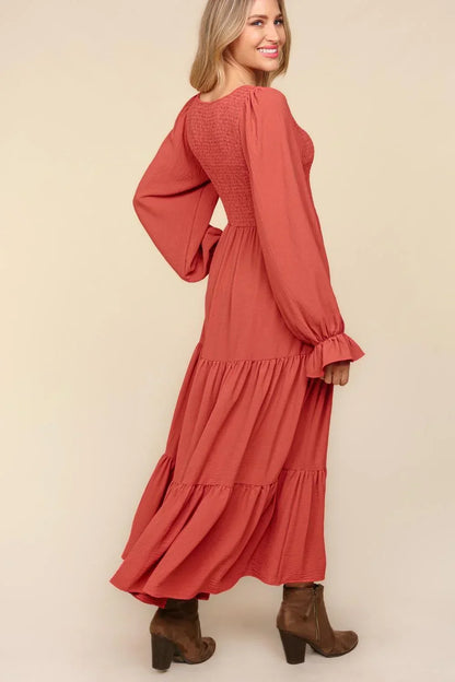 Woman wearing a long-sleeve, tiered rust maxi dress with relaxed fit and brown ankle boots