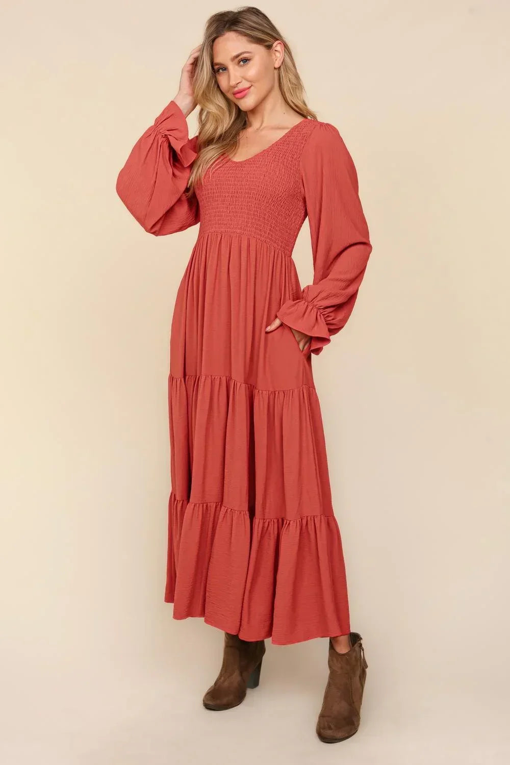 Woman wearing a rust-colored tiered maxi dress with long sleeves and brown ankle boots
