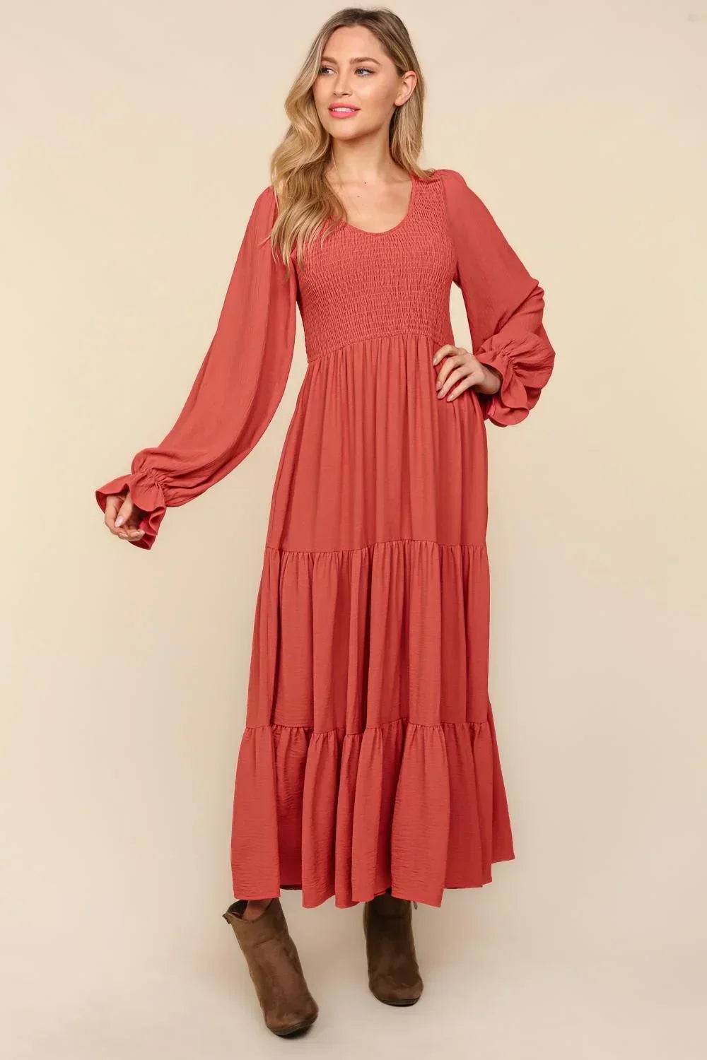 Woman wearing a rust-colored long tiered maxi dress with smocked bodice and puff sleeves